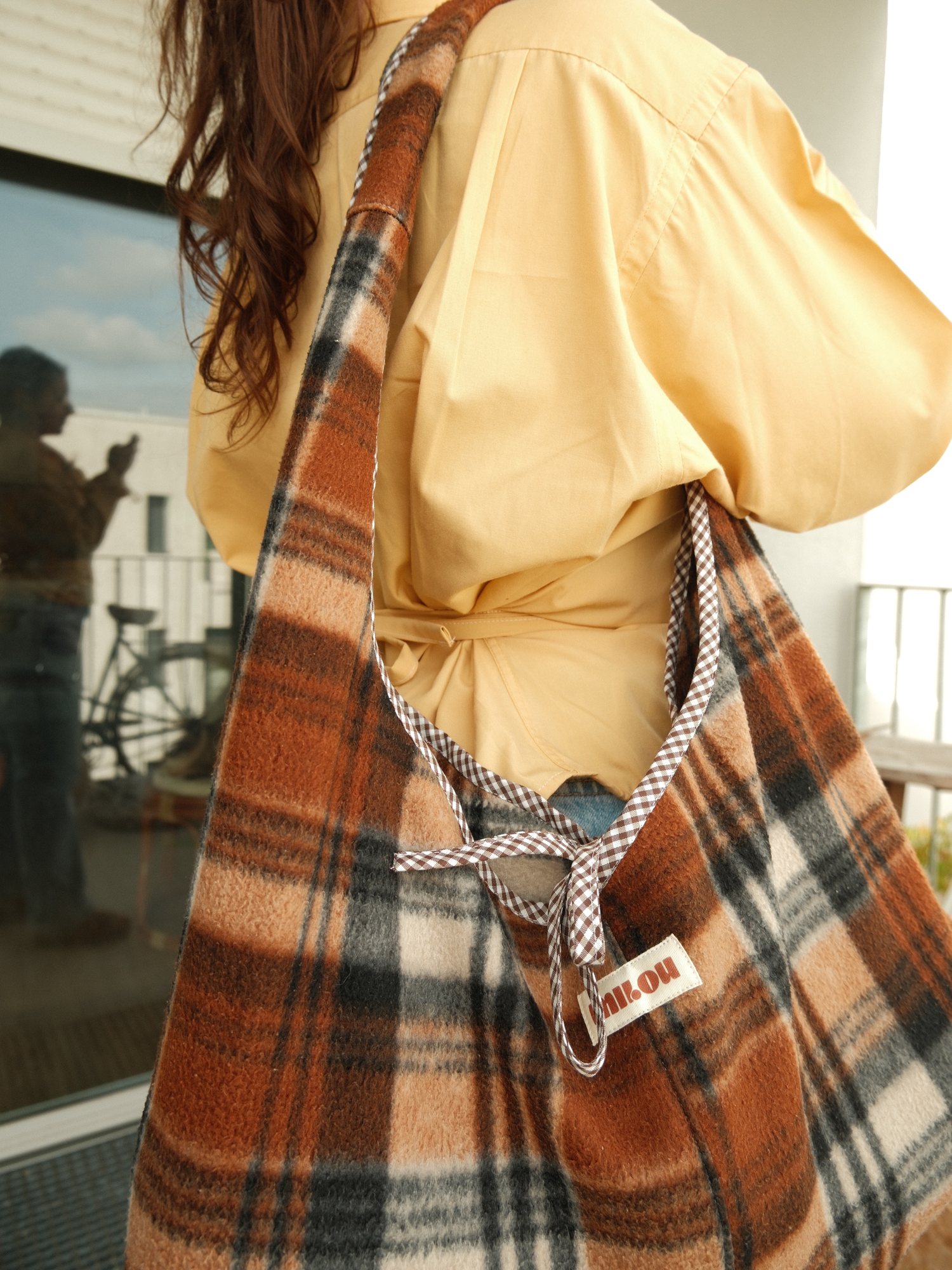 Sac en plaid à carreaux orange porté à l'épaule